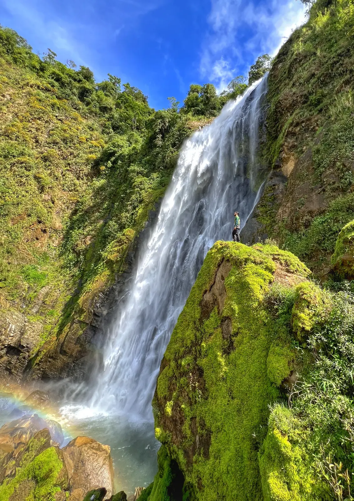 Catarata Metaponto, arcoíris y visitante sobre una roca cubierta de musgo